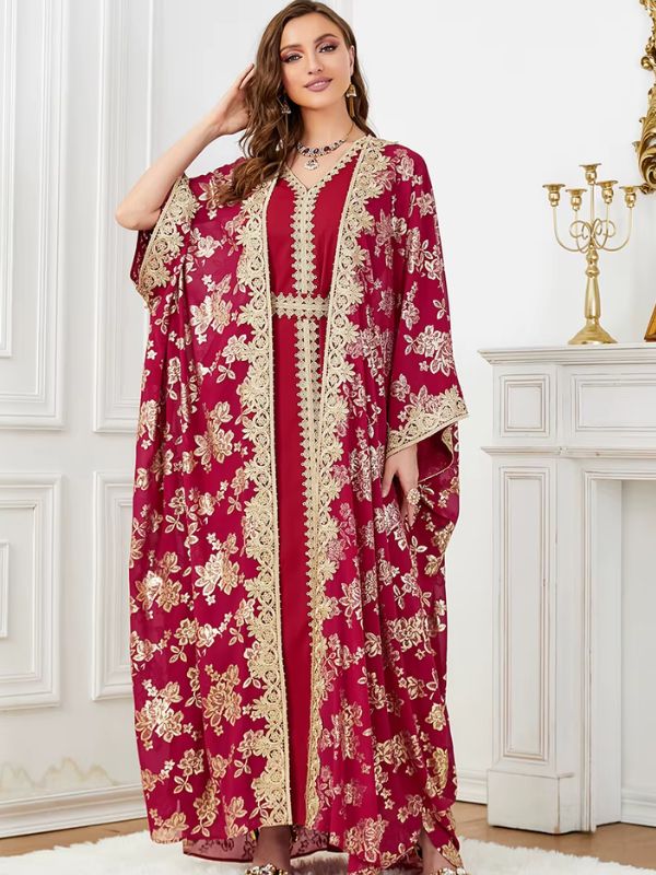 Une femme debout en caftan bordeaux orné de broderies dorées