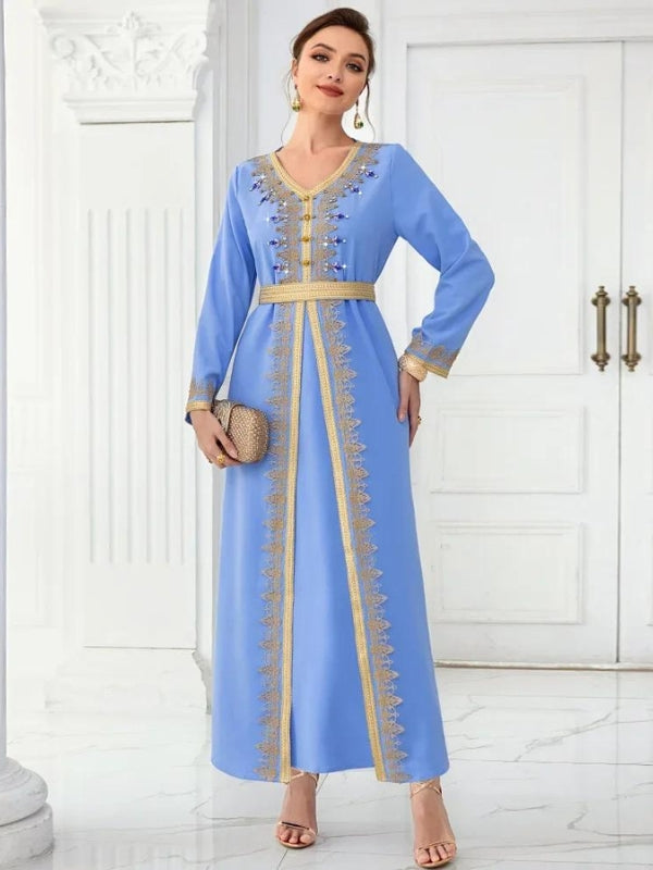 La femme porte un caftan bleu ciel orné de broderies dorées qui mettent en valeur le col en V, les manches, et descendent le long de l'ouverture frontale. Ces détails dorés ajoutent une touche d'élégance à sa tenue. La ceinture assortie à la taille accentue sa silhouette, tandis qu'elle accessoirise son look avec des sandales à talons et une pochette dorée. Sa coiffure relevée met en avant ses boucles d'oreilles pendantes, complétant ainsi un ensemble chic et sophistiqué, parfait pour des occasions formelle