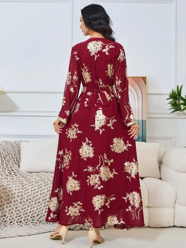La femme sur cette image est vue de dos, mettant en valeur le dos du caftan bordeaux richement orné de motifs floraux dorés. Le caftan est attaché à la taille avec une ceinture qui forme un nœud à l&#39;arrière, ajoutant une touche élégante à la tenue. Les manches longues et la longueur complète du caftan créent un effet fluide et gracieux. Les motifs dorés se détachent magnifiquement sur le tissu bordeaux, accentuant l&#39;aspect luxueux de la tenue