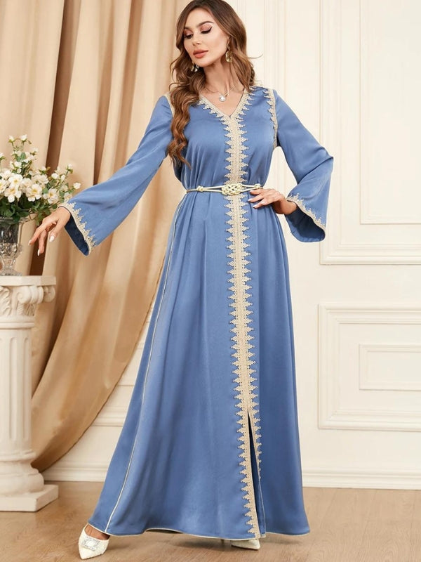 La femme est vêtue d'un élégant caftan bleu clair, qui présente une coupe longue et fluide, accentuée par des détails dorés le long du bord avant et des manches. Le caftan est resserré à la taille par une ceinture dorée, ajoutant une touche de structure à la tenue. Les manches évasées et le décolleté en V orné de broderies dorées soulignent la finesse et la sophistication du design