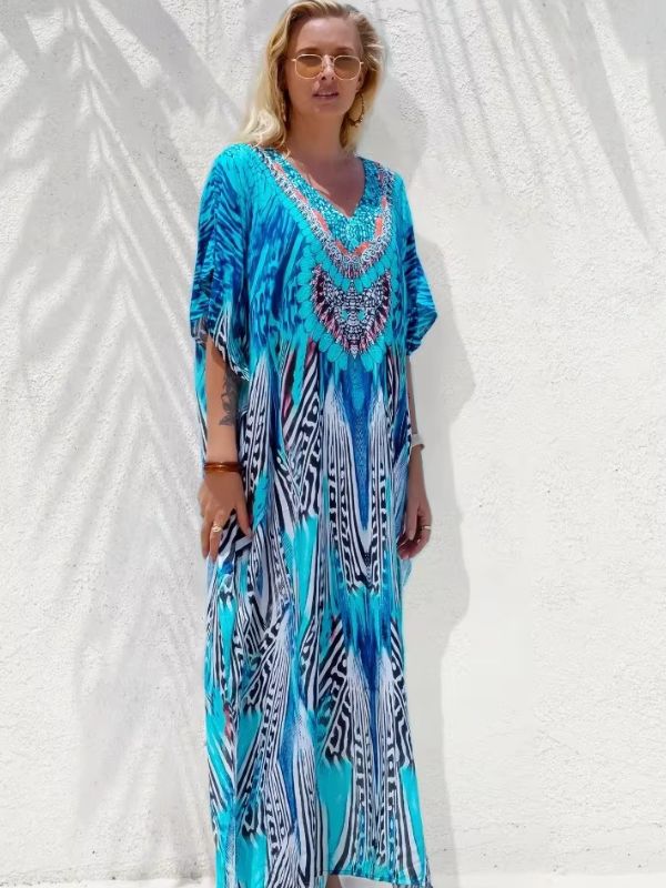 Une femme porte une djellaba turquoises et imprimés orientaux, posant avec élégance sous un ciel ensoleillé