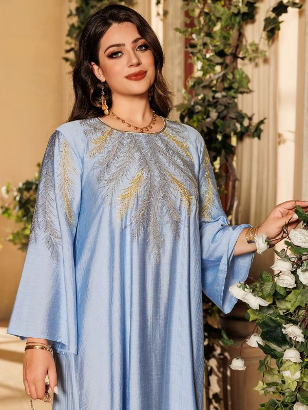 Une femme porte une djellaba bleu clair avec des broderies dorées