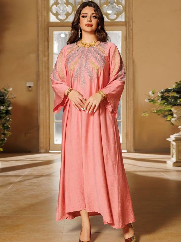 Une femme croise les mains et porte une djellaba rose