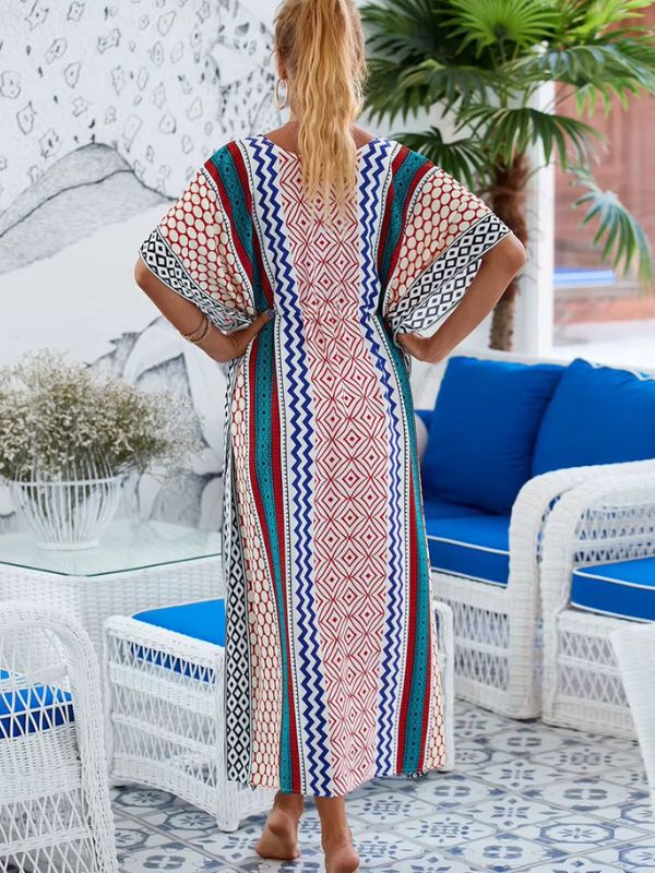 Une femme porte une djellaba longue aux motifs géométriques colorés, vue de dos dans un décor méditerranéen