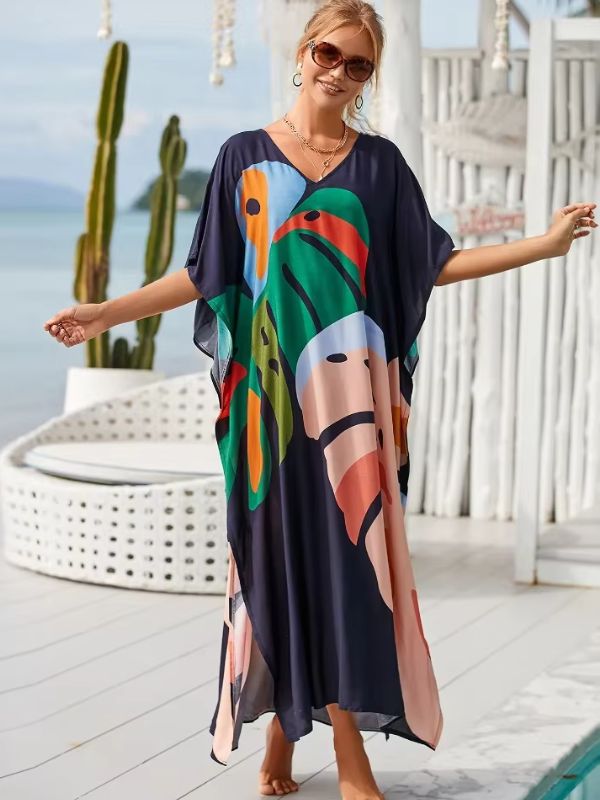 Une femme souriante en djellaba colorée pose sur une terrasse ensoleillée avec vue sur l’océan