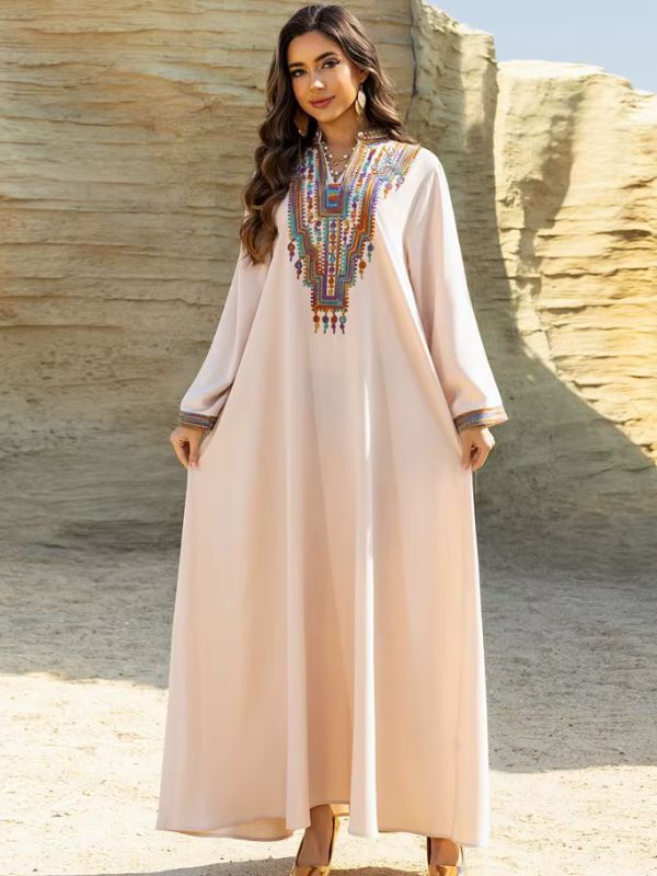 Une femme porte une djellaba beige ample sur plage