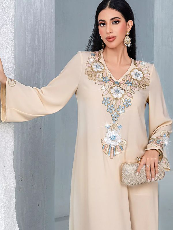 Gros plan sur la broderie florale en relief de la djellaba beige, encolure en V et motif central orné de strass