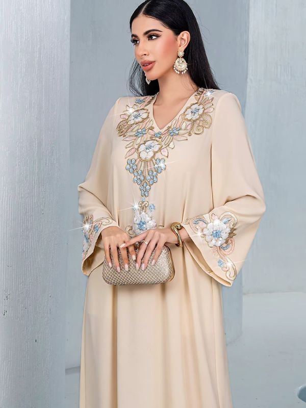 Djellaba marocaine beige brodée, vue de face à mi-corps avec pochette dorée, broderie du col et des manches
