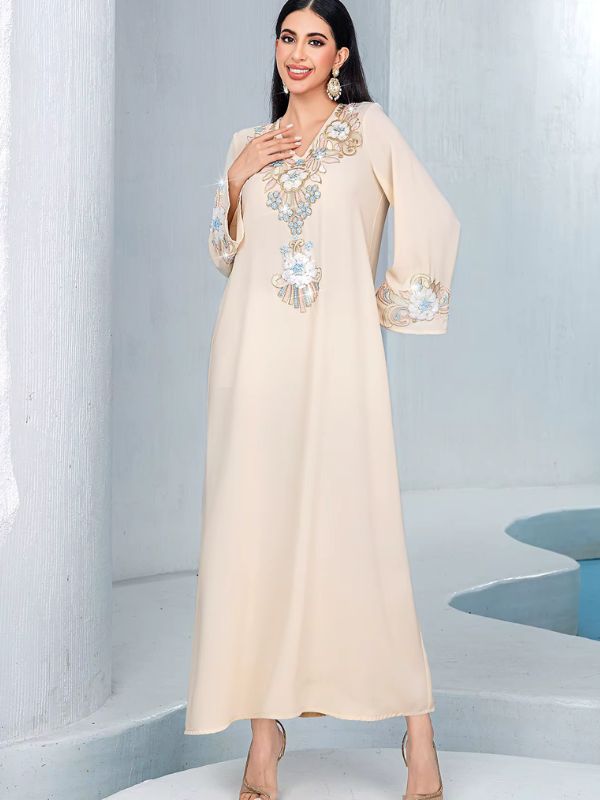 Djellaba marocaine beige, vue de face, main sur la poitrine, broderie florale à l'encolure en V
