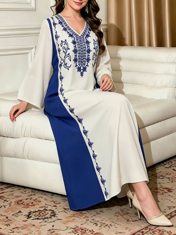 Djellaba marocaine blanche et bleu roi, mannequin assise sur un canapé blanc, jupe ample et guirlande de motifs bleus