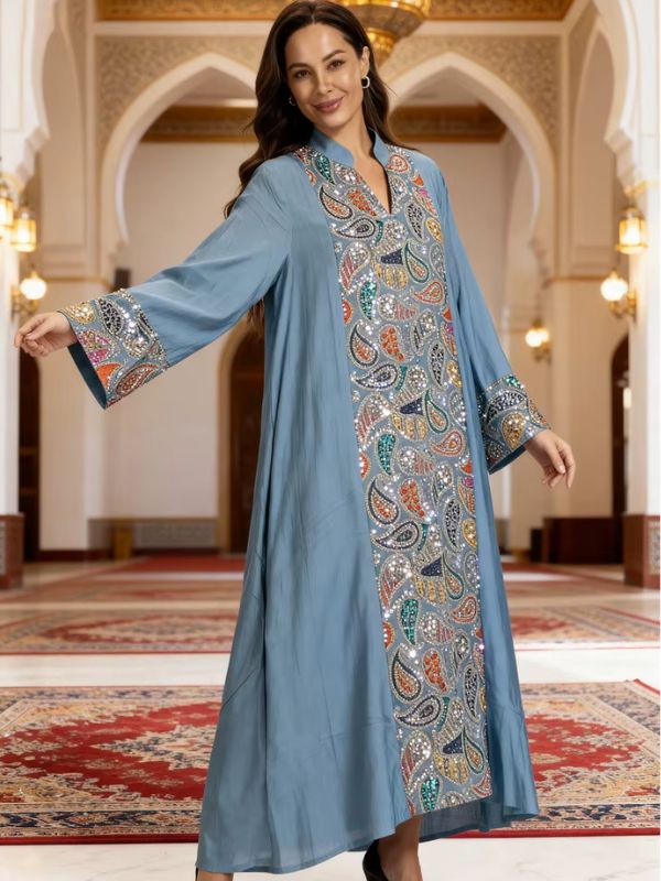 Djellaba marocaine bleu gris, vue de face, bras écartés montrant les manches amples aux poignets brodés de motifs cachemire et la bande centrale pailletée