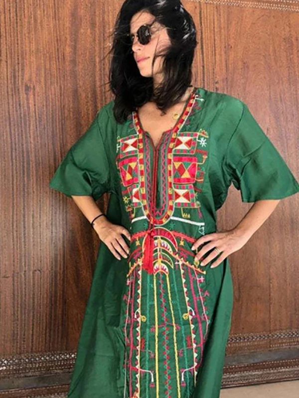 Gros plan sur une femme vêtue d’une djellaba verte traditionnelle avec un riche motif berbère multicolore sur le devant