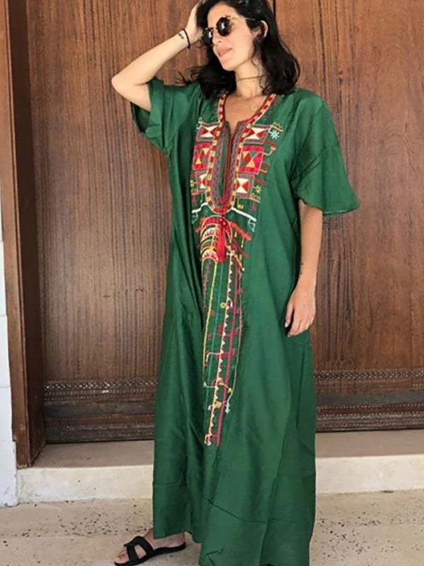 Femme debout en sandales noires, habillée d’une djellaba marocaine émeraude brodée de symboles amazighs