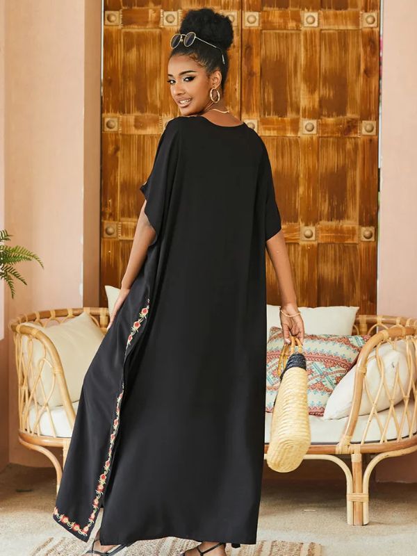 Femme de dos portant une djellaba noire ornée de broderies florales sur les côtés, tenant un sac en osier