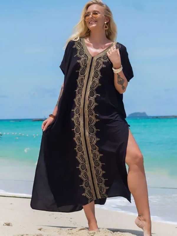 Femme souriante en djellaba noire à décorations dorées, posant face à la mer turquoise