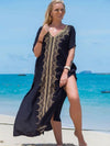 Femme en djellaba noire fendue sur le côté, marchant pieds nus sur une plage tropicale