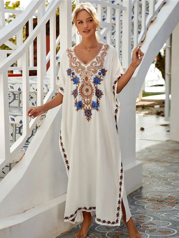 Femme marchant dans une villa en djellaba blanche brodée de doré, sous un ciel ensoleillé