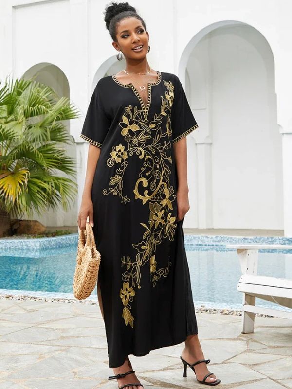 Une femme portant une djellaba noire brodée de doré près d’un décor marocain