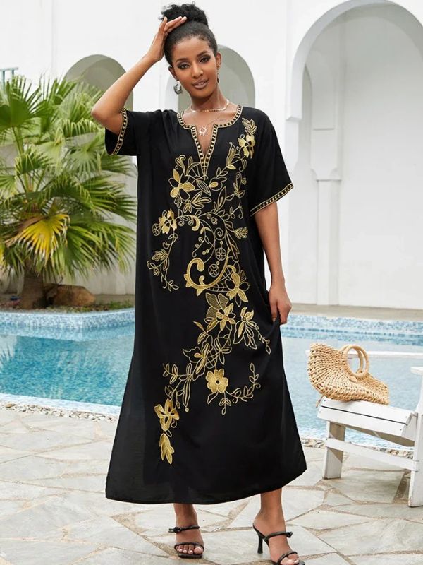 La djellaba marocaine noire aux motifs floraux dorés mise en valeur par une femme souriante