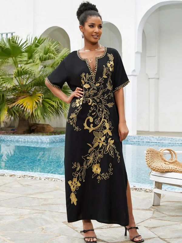 Femme debout en djellaba noire brodée dorée posant près d’une piscine orientale