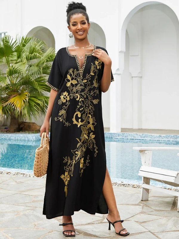 Une femme sourit en portant la djellaba marocaine noire brodée dorée avec un sac en paille