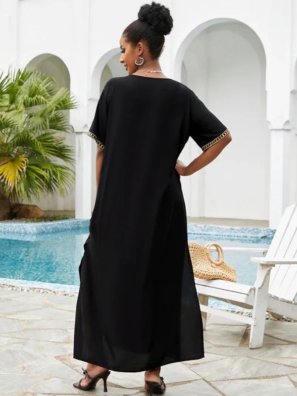 Une femme porte la djellaba marocaine noire brodée dorée vue de dos près d’une piscine