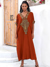 Femme en djellaba marocaine orange, posant dans un décor marocain traditionnel