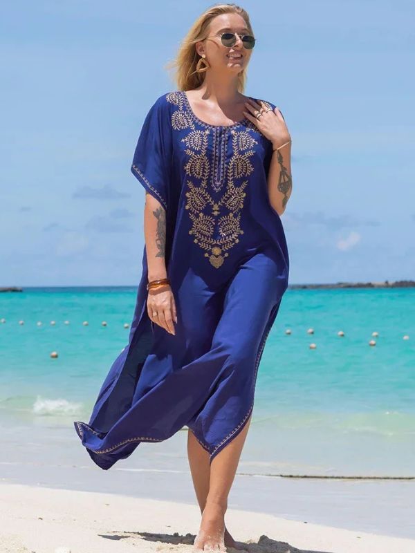 Femme marchant pieds nus sur le sable en djellaba bleu roi avec motifs dorés, en bord de mer turquoise