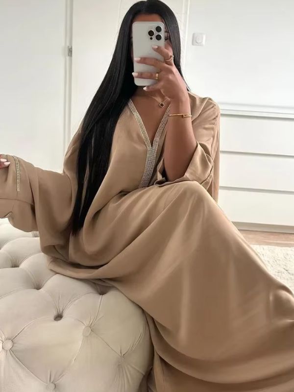 Une femme assise sur un lit qui porte une djellaba beige