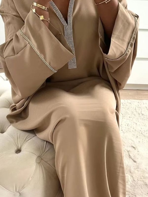 Une femme assise sur un lit qui porte une djellaba beige