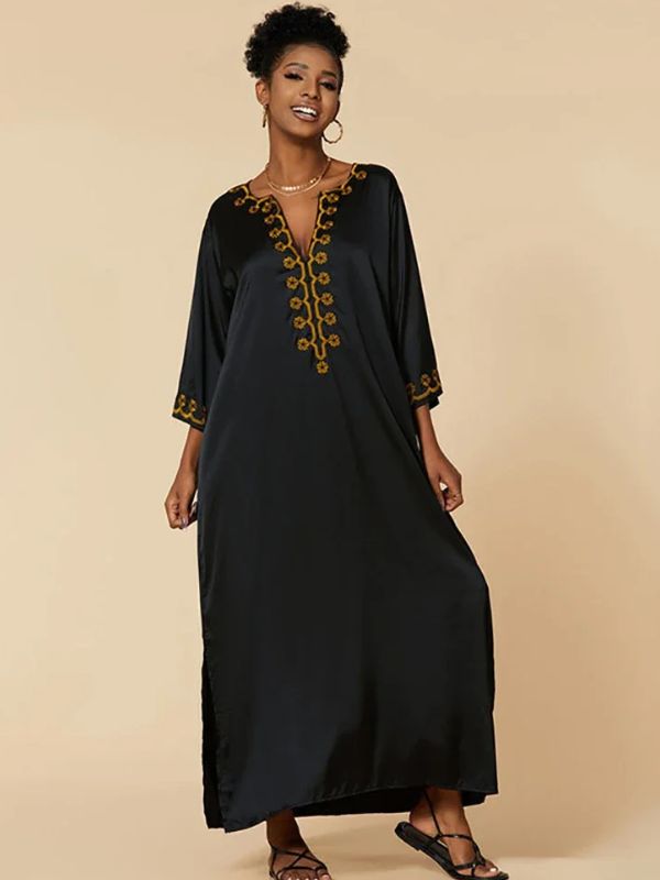 Femme en djellaba marocaine noire fluide, col en V brodé, posant debout