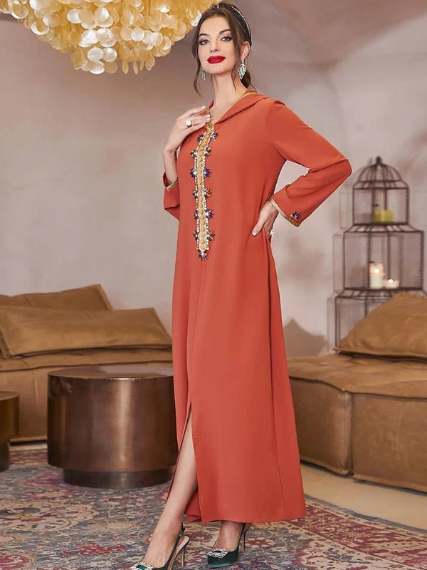 Une femme vêtue d&#39;une élégante djellaba orange. Cette djellaba se distingue par une broderie délicate et détaillée ornant le devant, ajoutant une touche sophistiquée et traditionnelle au vêtement. Les broderies sont rehaussées par des perles et des éléments décoratifs qui apportent un éclat subtil. La coupe de la djellaba est longue avec une fente discrète à l&#39;avant, offrant une allure à la fois modeste et moderne