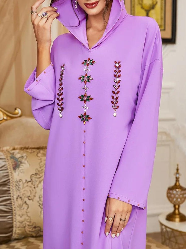 La djellaba lavande illustrée ici se distingue par son allure élégante et ses détails ornés. La capuche ajoute une touche moderne tout en maintenant le style traditionnel. Le devant de la djellaba est embelli par des broderies complexes et colorées qui rehaussent la sophistication du vêtement. Les manches amples offrent un confort optimal tout en créant une silhouette fluide et gracieuse. Les détails perlés sur les poignets et le long de la djellaba ajoutent une touche subtile de glamour
