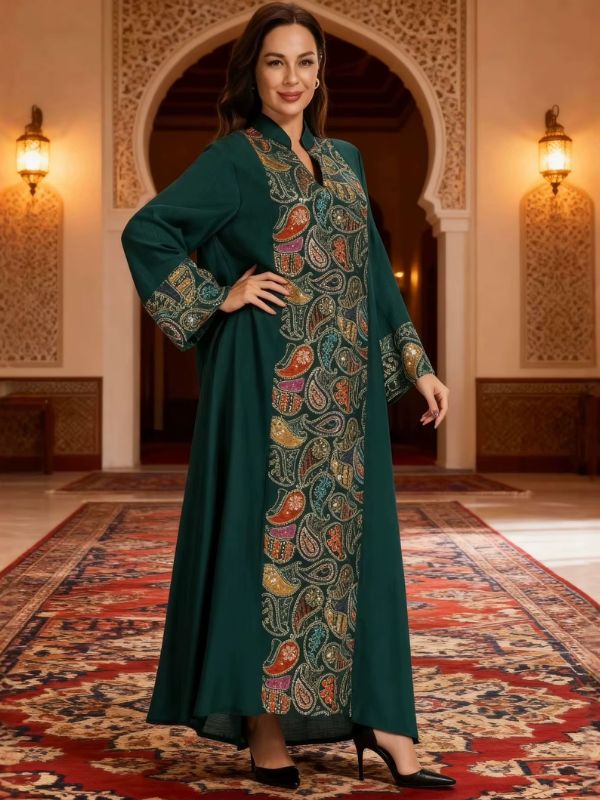 Djellaba marocaine vert sapin, vue de face en pied, col montant à ouverture en V et large bande centrale de motifs cachemire brodés et pailletés, main sur la hanche