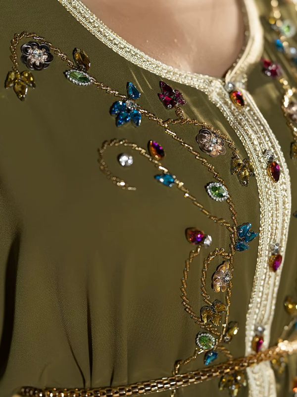 Gros plan broderies perlées et strass colorés sur djellaba verte olive