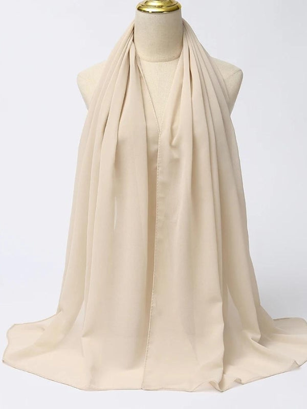 Un hijab blanc est présenté sur un mannequin, révélant sa texture fluide et légère. La couleur beige douce offre une touche de neutralité élégante, parfaite pour s'assortir avec une variété de tenues. Le tissu semble être de haute qualité, avec un drapé fluide qui ajoute du mouvement et de la grâce à l'ensemble. Ce hijab est idéal pour celles qui recherchent un look simple mais raffiné