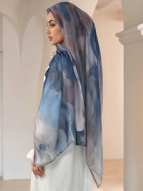 Hijab en coton imprimé bleu nuage, porté de profil, motif de nuages bleu denim, gris-mauve et ivoire
