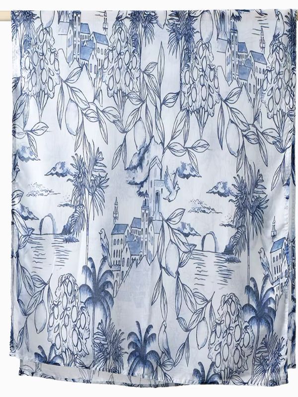 Hijab en coton imprimé bleu riviera, suspendu à une barre, décor bleu sur fond blanc avec bâtiments, palmiers, feuillages et oiseaux