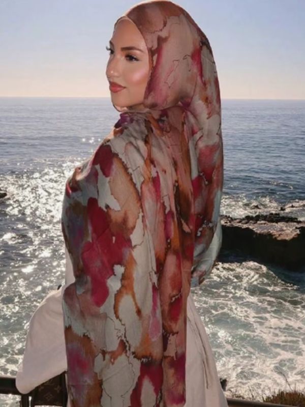 Hijab en coton imprimé rose framboise, porté de profil en bord de mer, aquarelle craquelée framboise, caramel et écru
