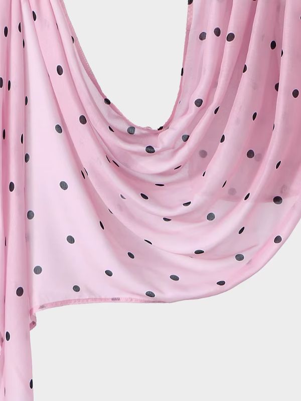 Hijab en coton imprimé rose à pois noirs, drapé en plis, fond rose pâle semé de pois noirs
