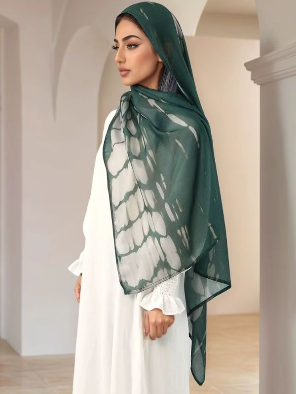 Hijab en coton imprimé vert forêt, porté de profil, motifs tie-dye ivoire sur fond vert profond, bord foncé