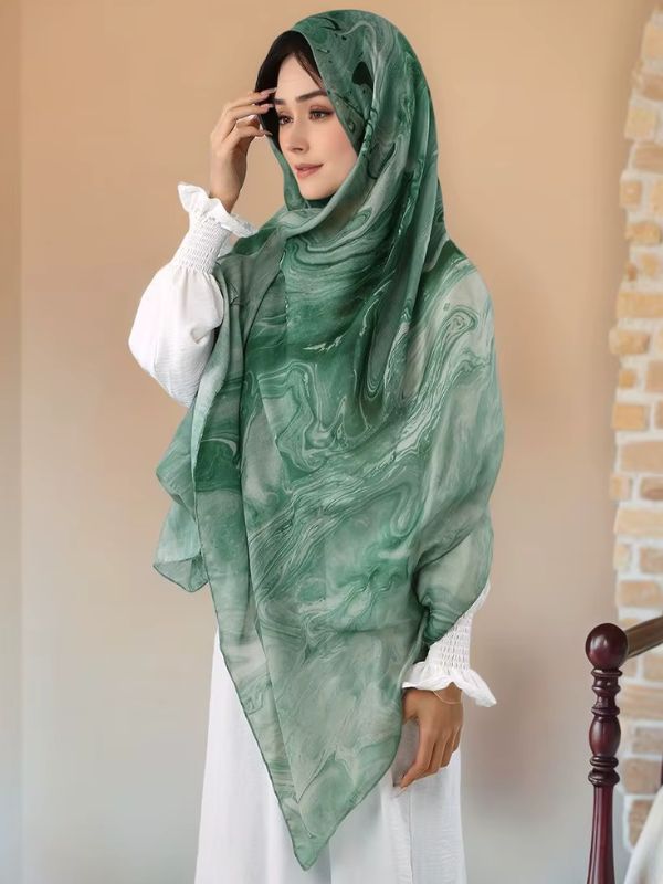 Hijab en coton imprimé vert jade, porté, volutes de marbre vert sur fond vert d'eau, voile drapé sur la tête et les épaules