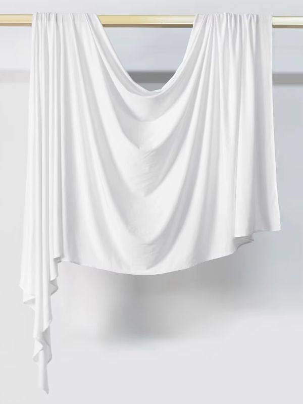 Hijab en jersey blanc suspendu et drapé sur une tringle dorée, présenté sur fond blanc