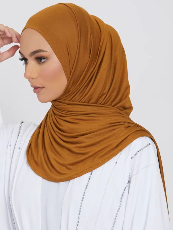 Une femme porte un hijab de couleur caramel doré