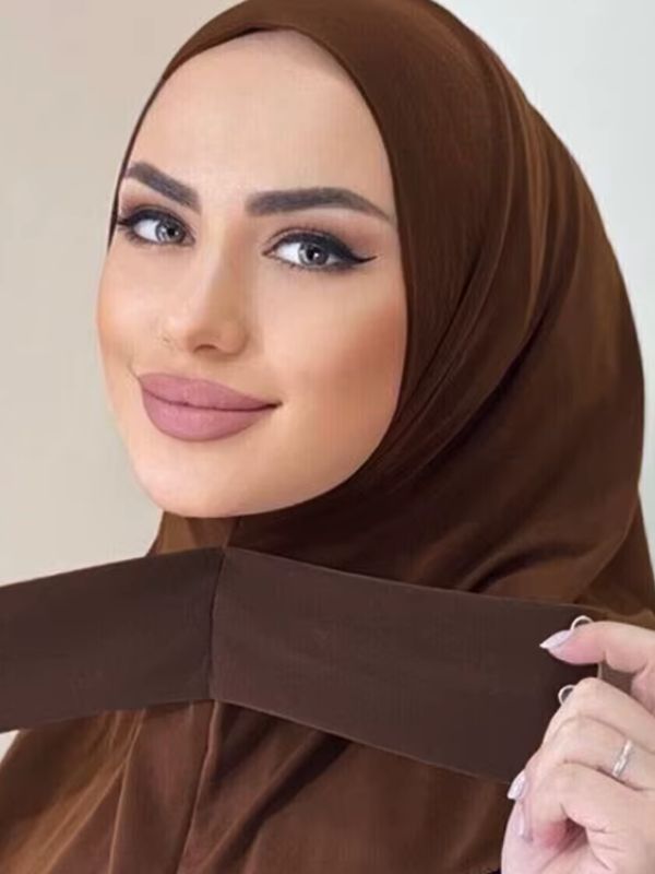 Hijab jersey premium instantané marron cacao, porté, bande croisée tenue à la main, bouton visible à son extrémité