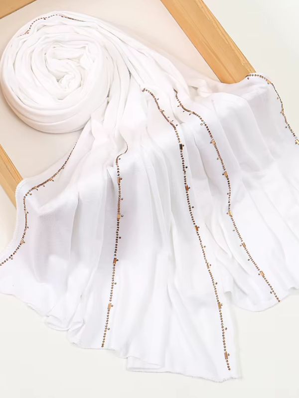 Hijab jersey premium strassé blanc, enroulé et drapé dans un cadre en bois, lignes de strass dorés sur toute la longueur