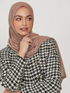 Femme portant un hijab en jersey de couleur taupe, habillée d&#39;une veste en tweed noir et blanc