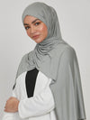 Femme posant de visage avec un hijab en jersey vert pierre, adoptant un style sobre