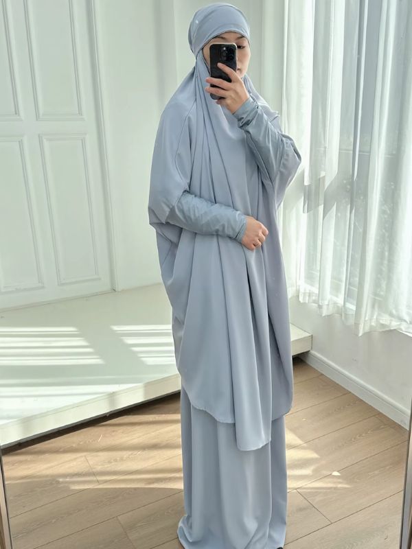 Jilbab femme gris bleuté vu de trois quarts, grand haut ample à manches larges, poignets ajustés et jupe longue