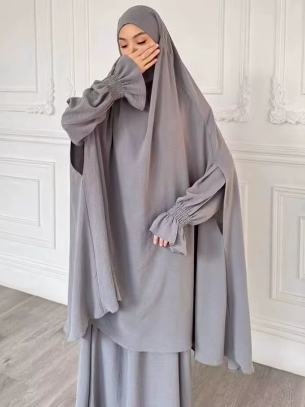 Jilbab femme deux pièces gris, grand haut à capuche aux manches larges et jupe longue, vue de face, main devant le visage